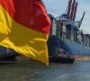 Containerschiff im Hafen und Deutschlandflagge im Vordergrund
