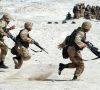 Soldaten mit Gewehren laufen durch eine Wüste