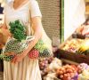 Frau im Supermarkt mit Netzen, in denen Obst und Gemüse steckt